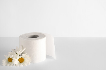 Toilet paper roll with chamomile flowers on white background