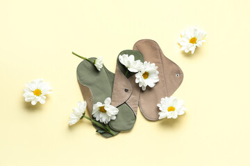 Composition with reusable menstrual pads and chamomile flowers on color background
