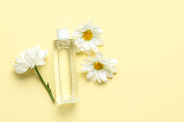 Bottle of cosmetic product with chamomile flowers on color background
