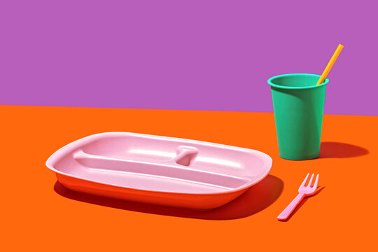 Colorful plastic tableware on a vibrant background
