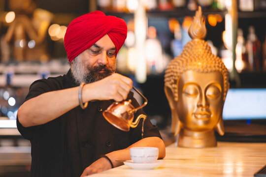 Sikh barista pouring coffee in stylish cafe setting - Powered by Adobe