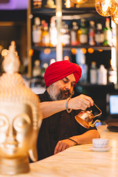Sikh barista carefully pouring tea in a cozy cafe setting