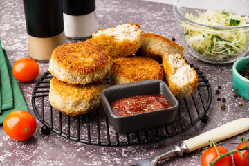 Grid of tasty meat cutlets with sauce on grey background