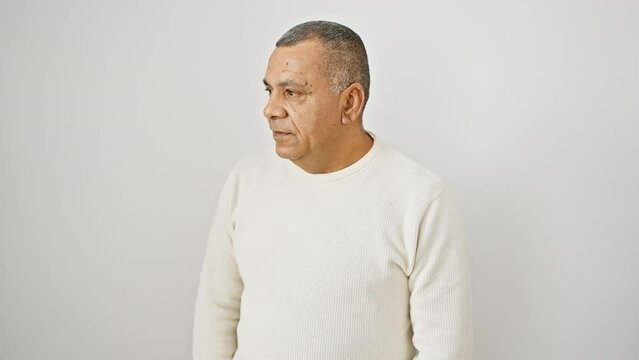 Thinking latin man in his middle age, confident attitude, wearing sweater, severe expression on white isolated background, handsome face reflecting mature confidence. doubtless, he stands certain