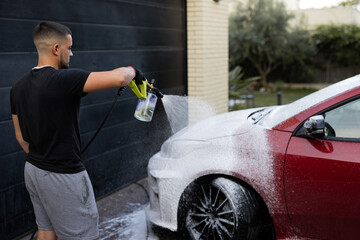 Man washing car with high-pressure foam sprayer
