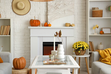 Interior of light living room with coffee table, chrysanthemum flowers and fireplace