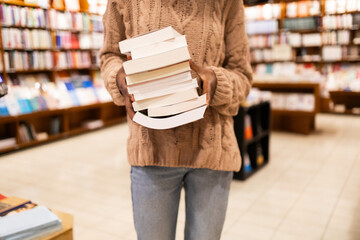 Person holding a stack of books in a library