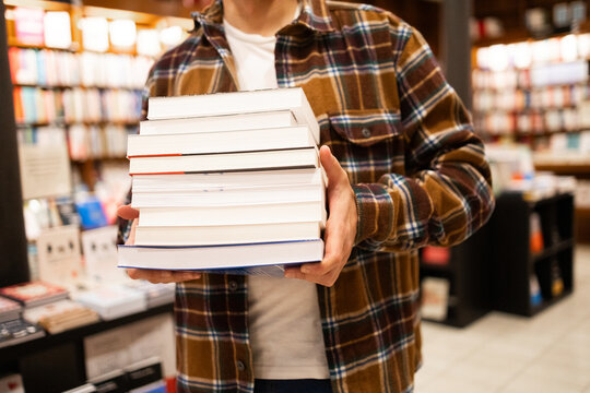 Person holding a stack of books at a bookstore