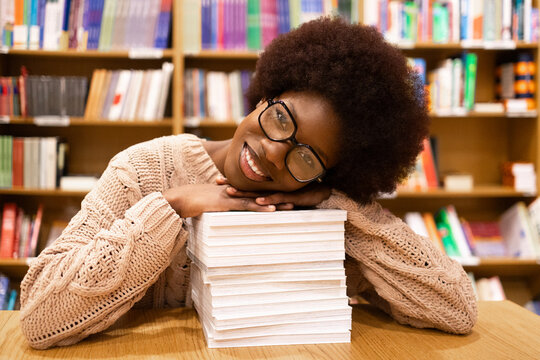Content African American woman in library with stack of books