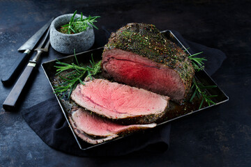 Traditional Commonwealth Sunday roast beef sliced with herbs and served as close-up on a rustic...