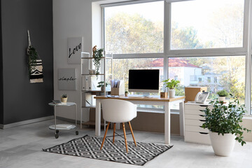 Interior of modern office with workplace, shelf unit and plants