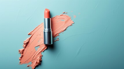 A peach-colored lipstick in a silver tube lies next to a large smear of the same color. The lipstick and smear are both isolated on a blue background with a soft focus. - obrazy, fototapety, plakaty