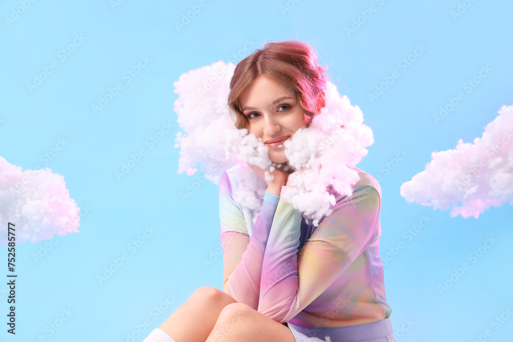 Wall mural Young woman with white clouds sitting on blue background