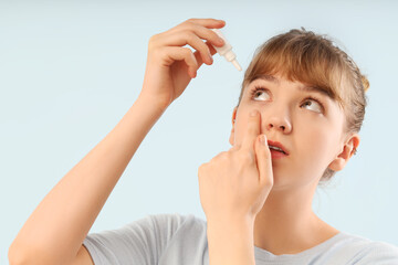 Young woman using eye drops on light background, closeup. Glaucoma awareness month