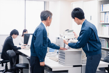 オフィスで電話機のメンテナンスをする作業員の男性
