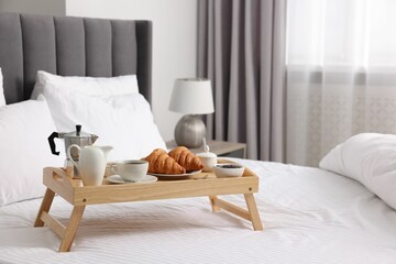 Tray with tasty breakfast on bed at home, space for text