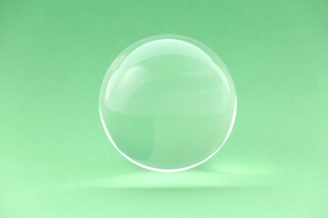 Transparent glass ball on light green background