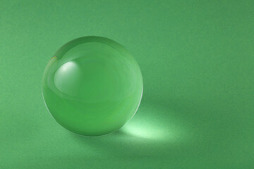Transparent glass ball on light green background. Space for text