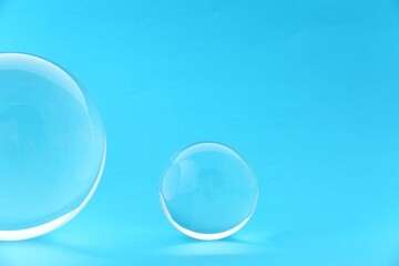 Transparent glass balls on light blue background. Space for text