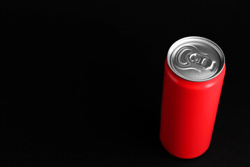 Energy drink in red can on black background, space for text