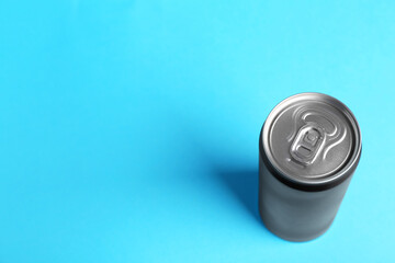 Energy drink in black can on light blue background, above view. Space for text