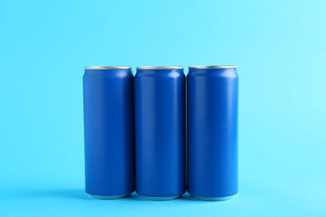 Energy drinks in cans on light blue background