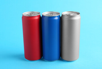 Energy drinks in colorful cans on light blue background