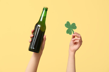 Hands with beer and clover on yellow background. St. Patrick's Day celebration