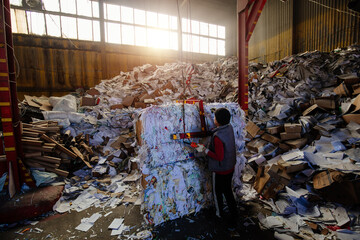 Worker packing paper at wastepaper recycling factory