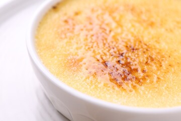 Delicious creme brulee in bowl on table, closeup