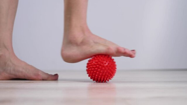 Close-up of a woman's foot on a massage ball with spikes. 