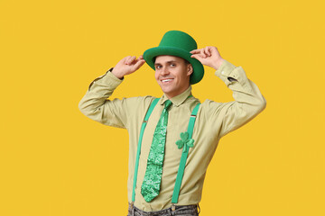 Happy young man in leprechaun's hat on yellow background. St. Patrick's Day