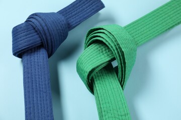 Colorful karate belts on light blue background, closeup