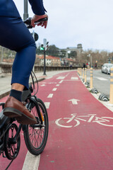 vertical portrait Closeup of businessman's leg pedaling on red bike lane in city