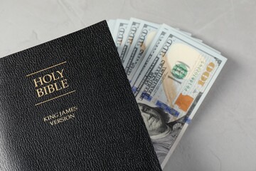 Holy Bible and money on grey table, top view