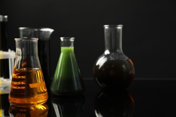 Laboratory glassware with different types of oil on black background