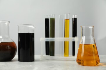 Laboratory glassware with different types of oil on white table - obrazy, fototapety, plakaty