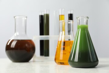 Laboratory glassware with different types of oil on white table, closeup