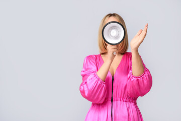 Fototapeta premium Mature woman with megaphone on grey background