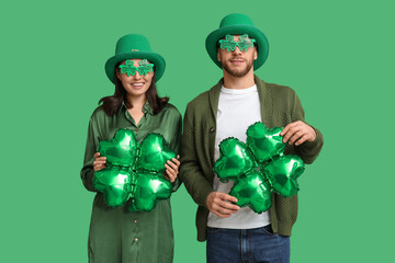 Beautiful young couple in leprechaun hats and decorative glasses with air balloons in shape of...