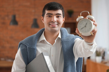 Young businessman with alarm clock and folder in office, closeup