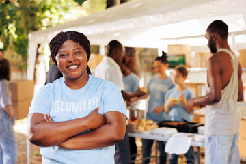 Enthusiastic black woman wearing blue t-shirt with arms crossed looks at camera. Portrait shot of...