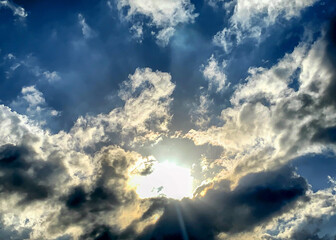 Brilliant blue skies with sun, sun rays, and golden clouds