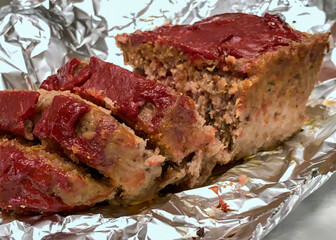 Sliced meatloaf sitting on aluminum foil