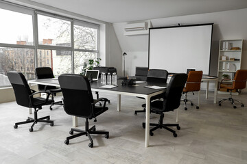 Table, armchairs and screen board prepared for business meeting in conference hall