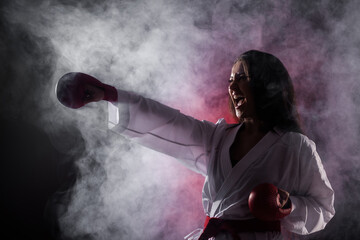 girl exercising karate punch against red fog background