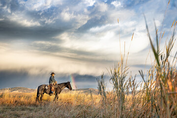 Fototapeta premium Colorado Cowboy riding blue roan quarter horse with storm clouds