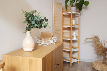 Vase with eucalyptus and books on commode in living room