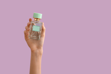 Female hand holding bottle of perfume on color background