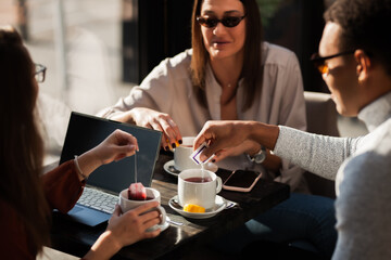 Three friends in a restaurant talking smiling and drinking tea. Business colleagues having a meeting after work or during coffee break at a cafe bar..